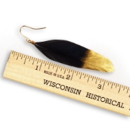 Black feather earring next to ruler reading about 2 inches in total length