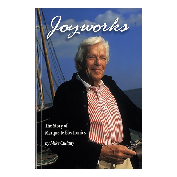 Joyworks cover featuring author Mike Cudahy dressed in red and white button down shirt with black jacket. In front of a sailboat on the dock.