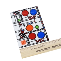 Rectangular refridgerator magnet with colorful, geometric designs by Frank Lloyd Wright. Shown with ruler showing 2.5 inch width.