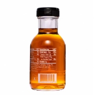 Small glass bottle of golden maple syrup. Side of bottle showing some nutritional components and ingredients.